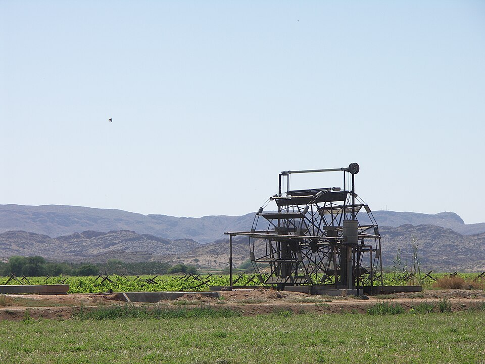 A waterwheel in Kakamas, Northern Cape, South Africa. The waterwheel is situated in an irrigation canal fed from the Orange River to supply water to the vineyards in the background.